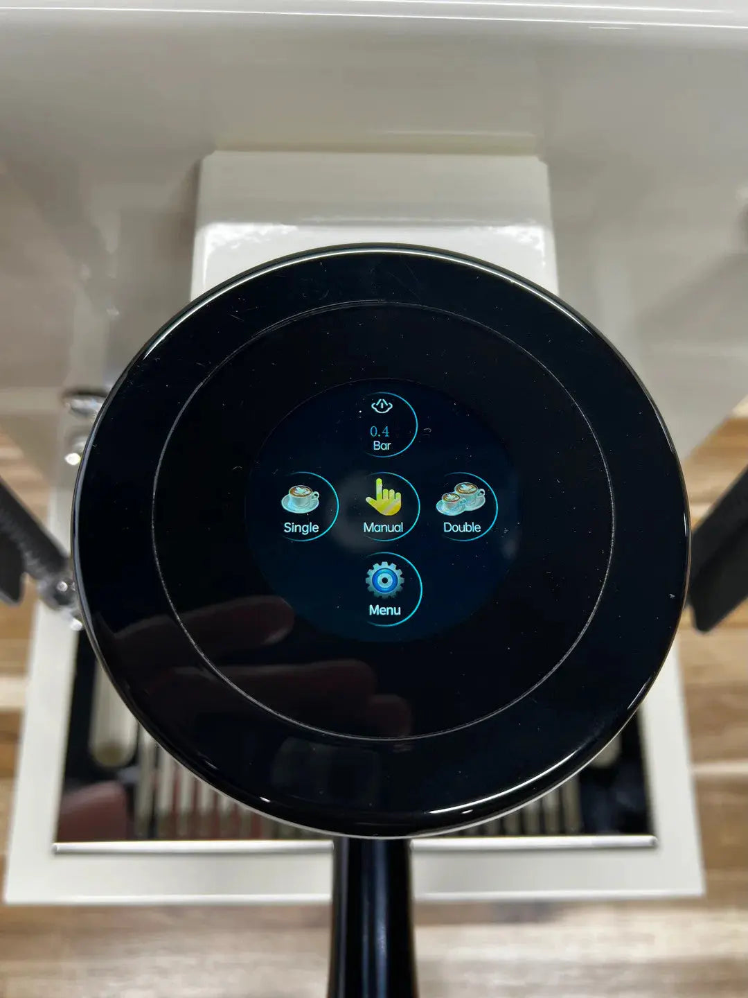 Turin-MC3 Close-up of a black circular coffee machine control panel with a touch screen displaying single, double, and menu options.